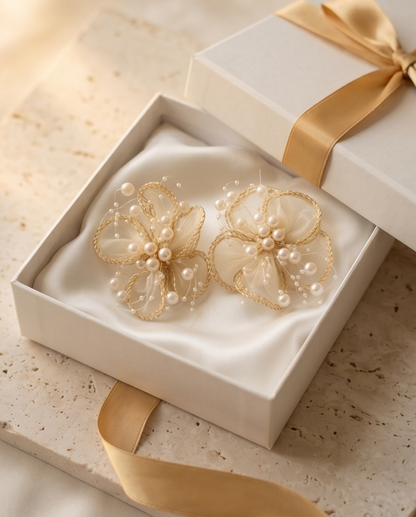 Gold floral earrings with pearls in a white box with a gold ribbon.