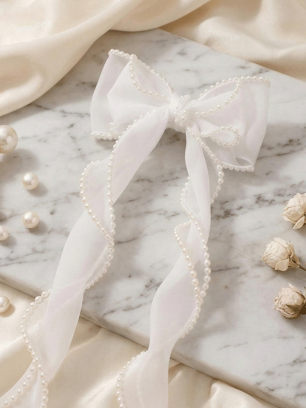White bow with pearls on a marble surface