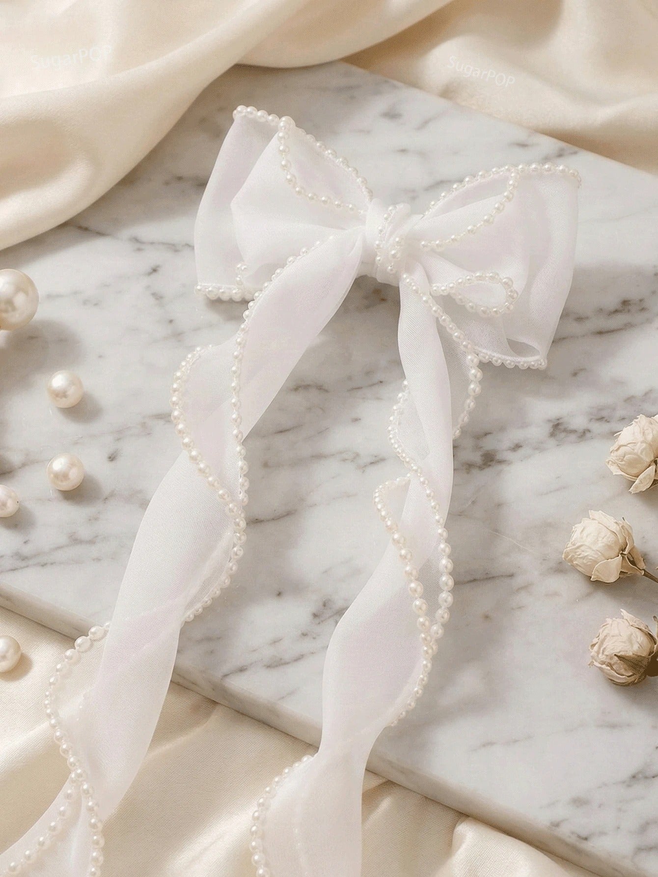 White bow with pearls on a marble surface