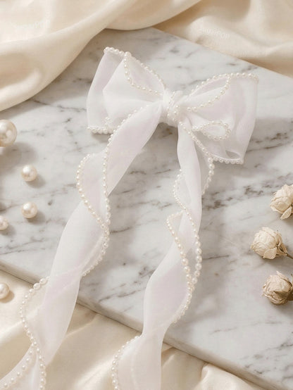 White bow with pearls on a marble surface