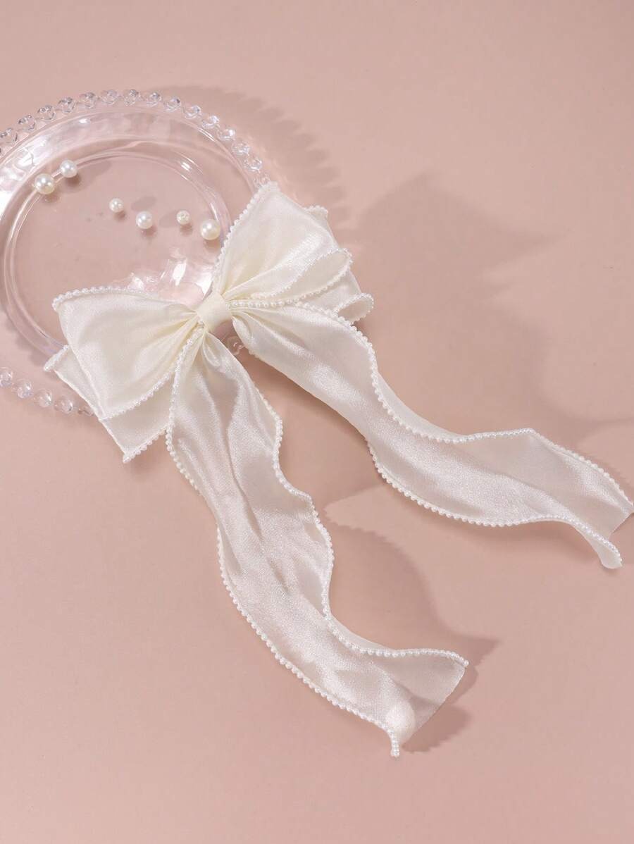 White bow with pearl accents on a pink background