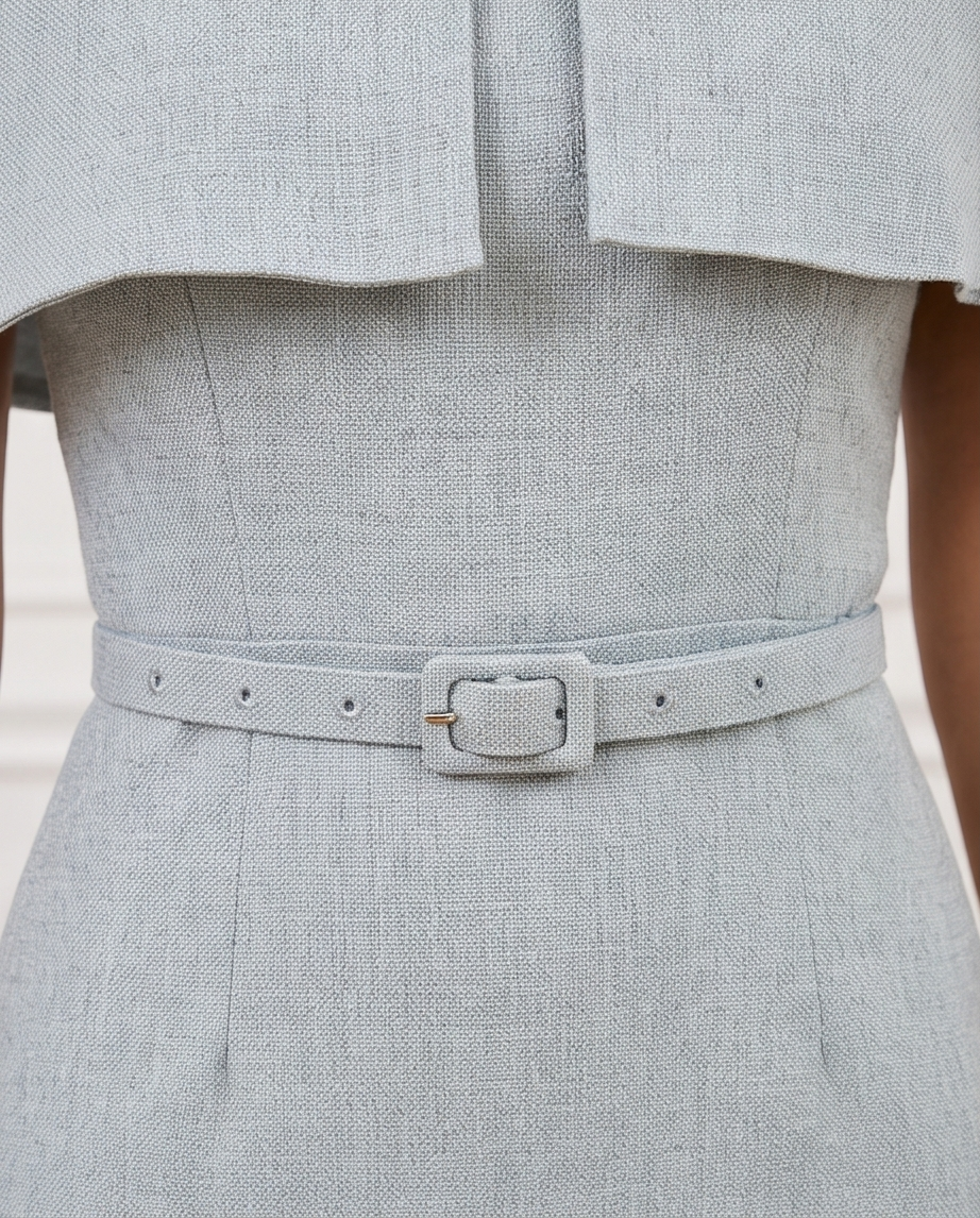 Women’s dusty blue midi dress with a cape-style shoulder overlay, matching buckle belt and gently flared skirt