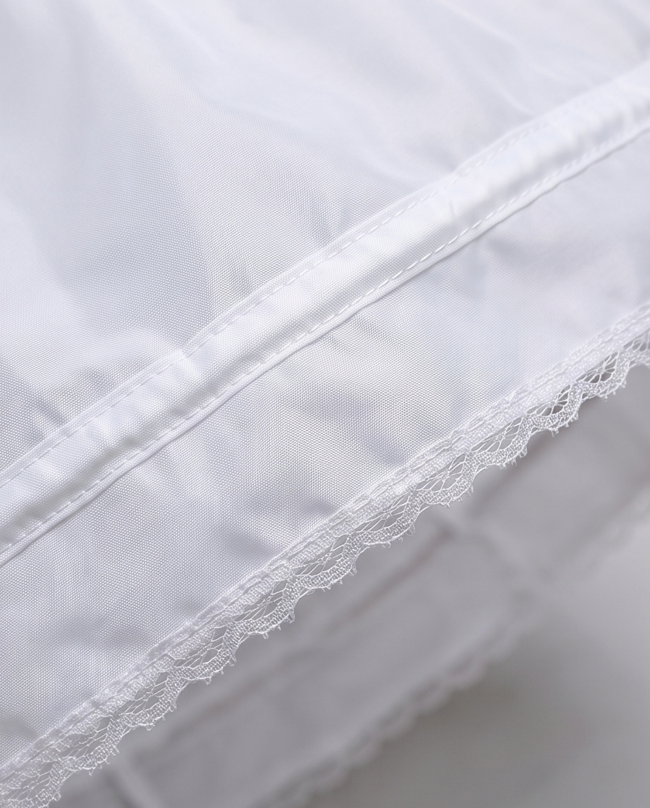 Close-up of white fabric with lace trim on a light gray background