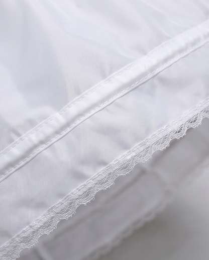 Close-up of white fabric with lace trim on a light gray background