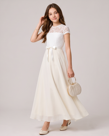 A woman modeling a white lace and chiffon maxi dress with a matching waist tie, holding a small pleated cream handbag against a light gray studio background.