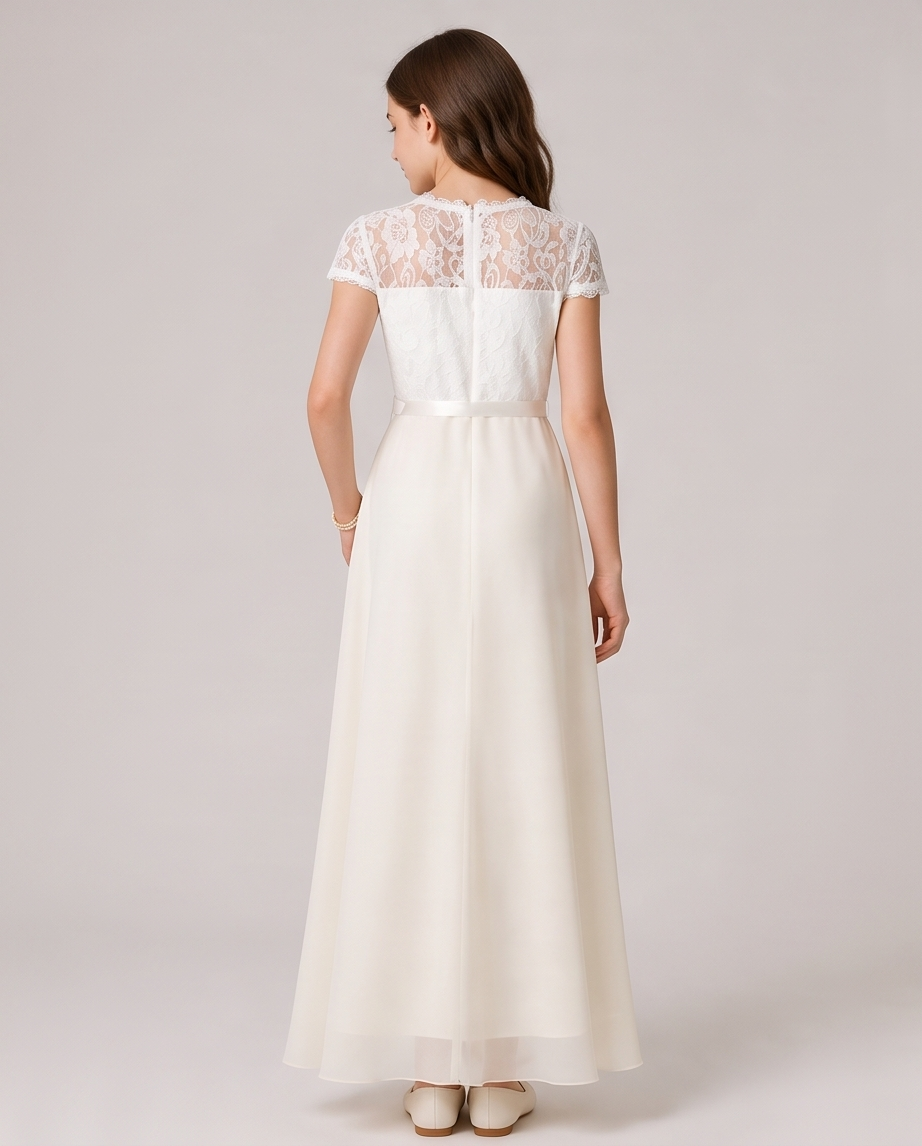 A woman viewed from the back wearing a floor-length ivory dress with a lace lace-embroidered bodice, cap sleeves, and a flowing chiffon skirt, set against a solid light gray studio background.