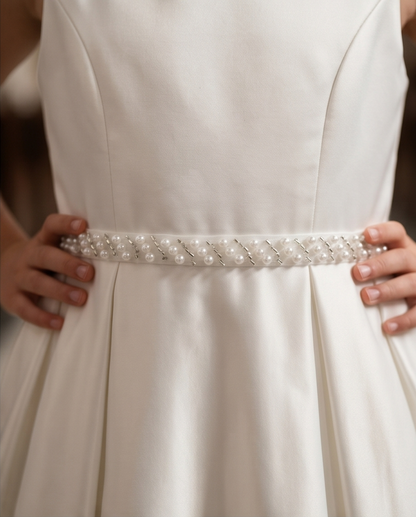 White dress with a decorative belt held by hands