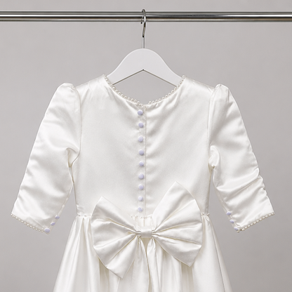 White dress with a bow on a hanger against a gray background