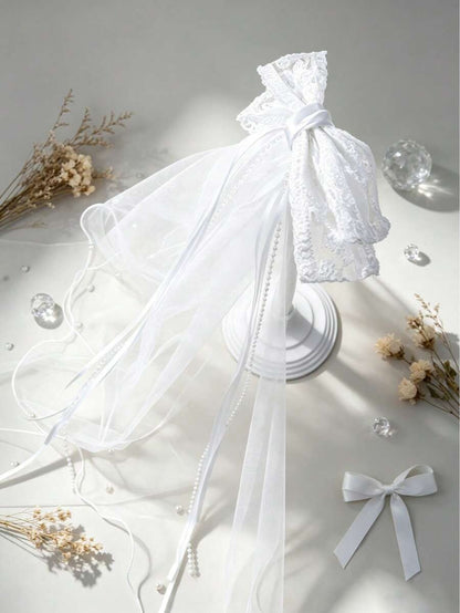 White lace veil headband with ribbons on a light gray background