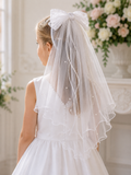 Young girl in a white dress with a decorative veil in a decorated room.