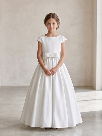 Young girl wearing a white dress with a bow belt against a neutral background