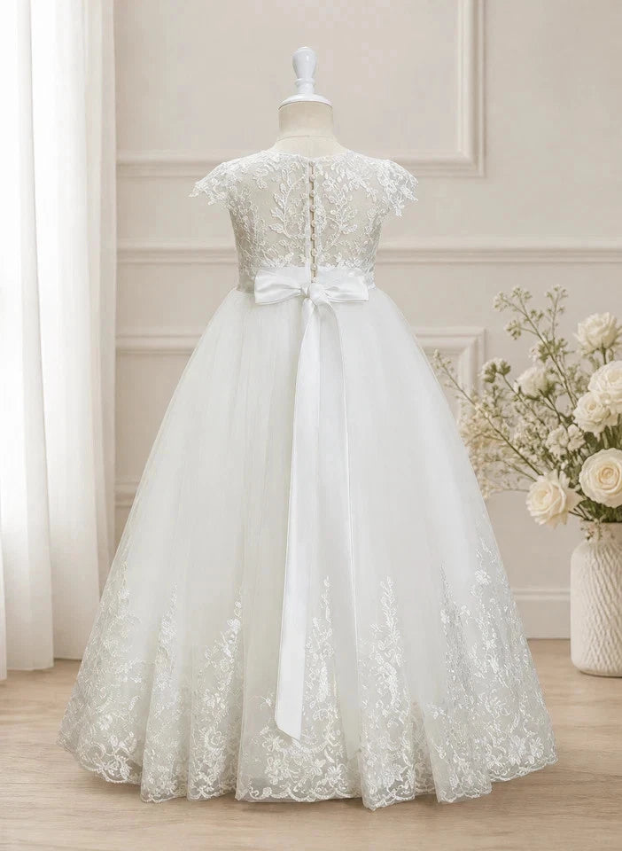 White lace dress on a mannequin with a floral arrangement in the background