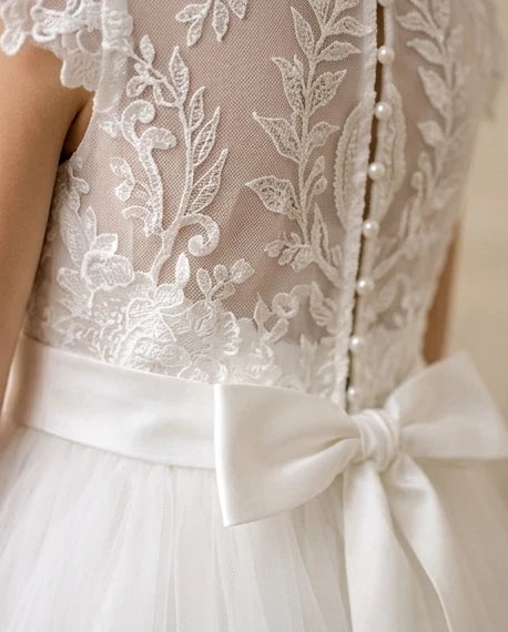 Close-up of a white lace dress with a bow detail