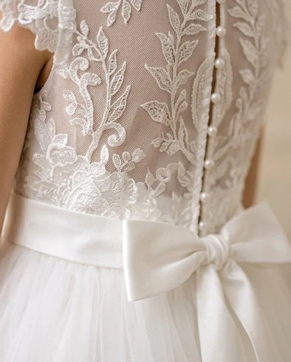 Close-up of a white lace dress with a bow detail